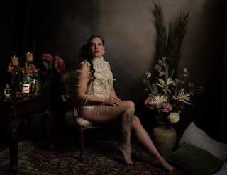 A woman poses elegantly in a dimly lit room.