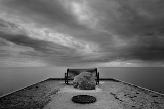 A lonely bench on a platform overlooking the ocean.