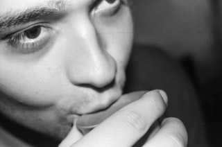 Close-up of a person drinking from a small glass.